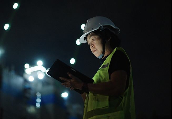 Women in a hard hat and hi-vis looking at a clipboard.