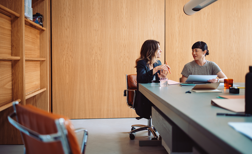 Two women in an office talking.