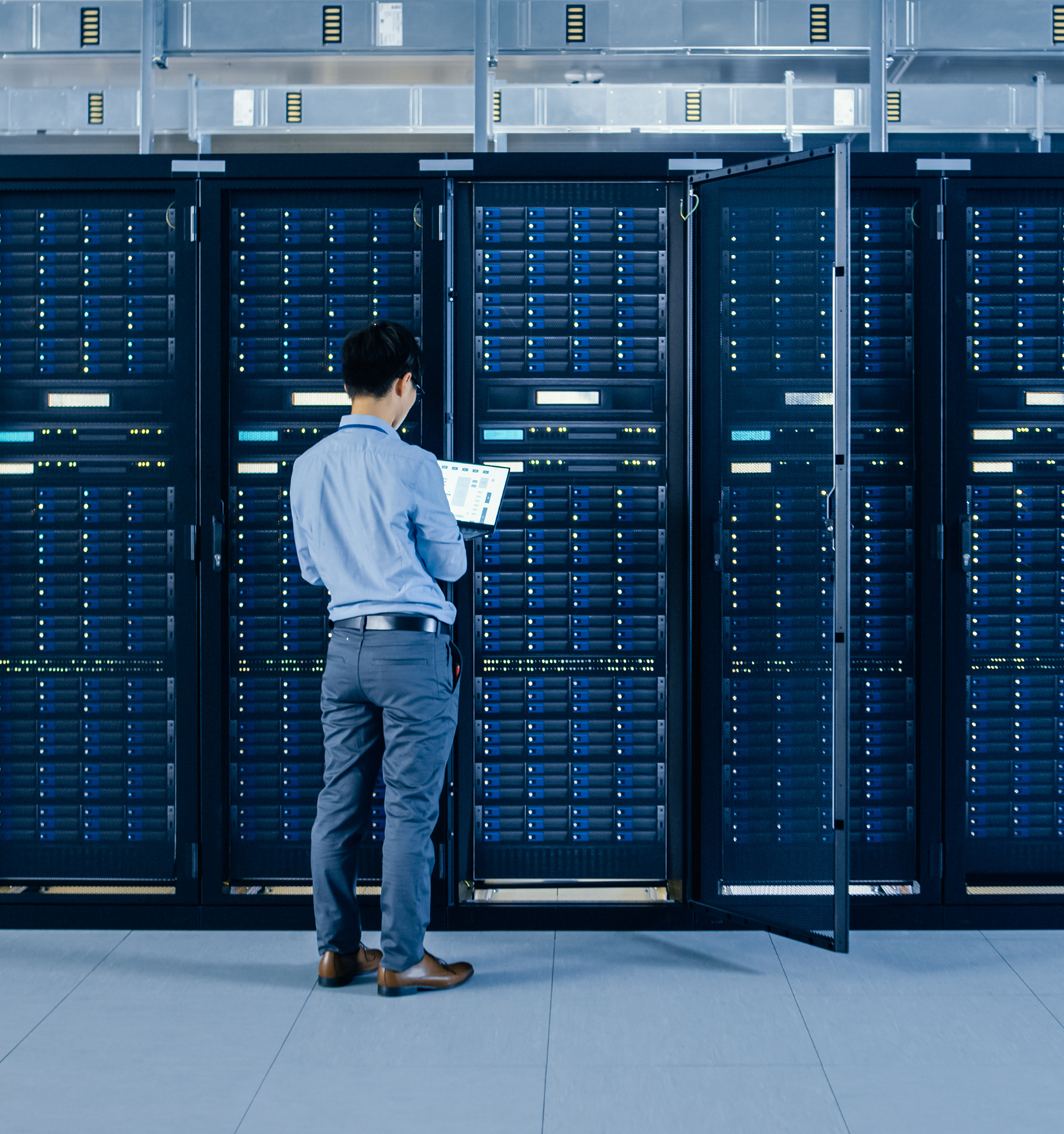A man with a laptop looking at servers