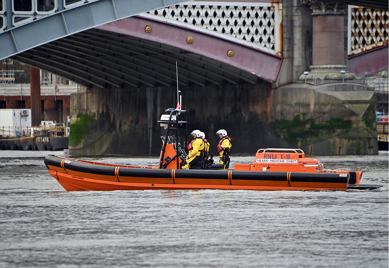A coastal safety boat with three members of the crew on it.