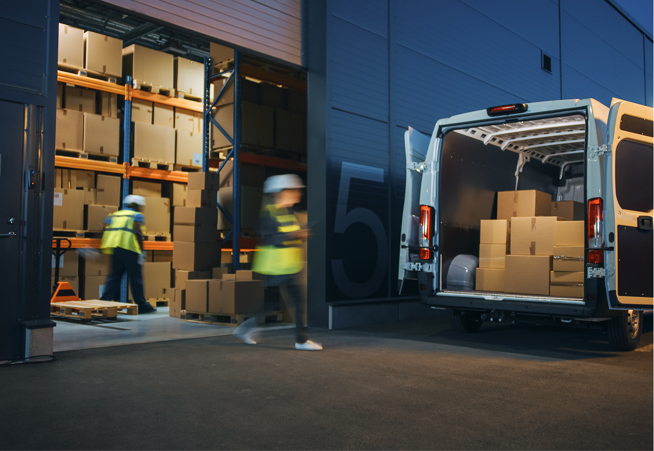 Two people loading a van with parcels from a loading dock.