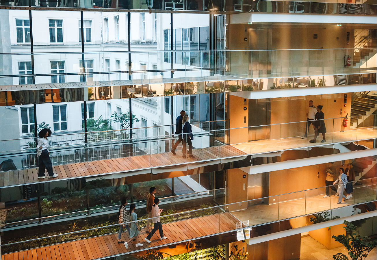 Multiple people walking on different floors of an office building.